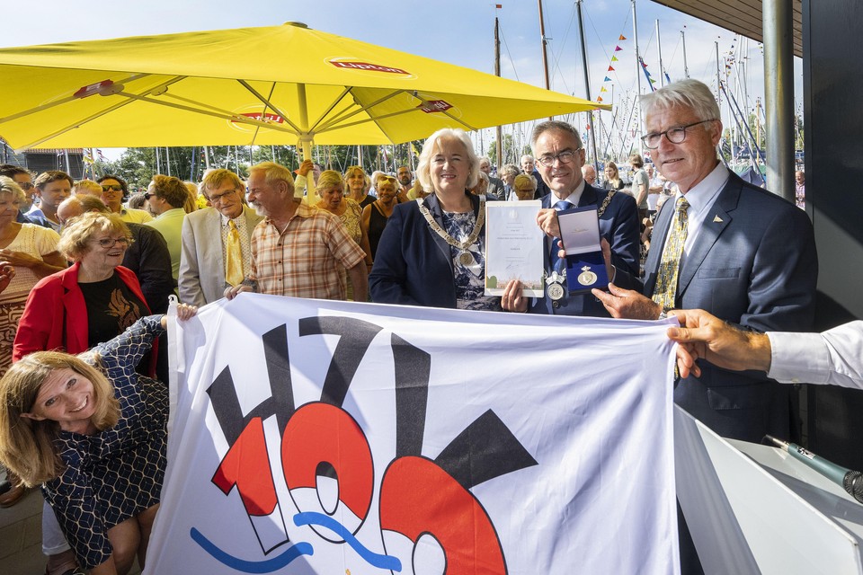 Voorzitter Norbert Alberts en de burgemeesters Marianne Schuurmans en Jos Wienen met de koninklijke erepenning en de nieuwe verenigingsvlag: met kroontje.