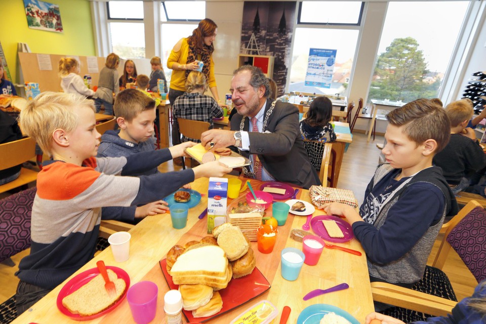 Daniël Mulder biedt burgemeester Jaap Nawijn een plak kaas aan tijdens het schoolontbijt op De Branding in Den Oever.