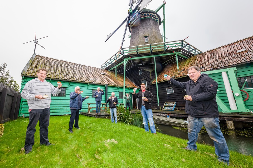 Vrijwilligers en bestuursleden van De Zaansche Molen heffen hun kopje koffie op het 400-jarig bestaan van oliemolen Het Pink.