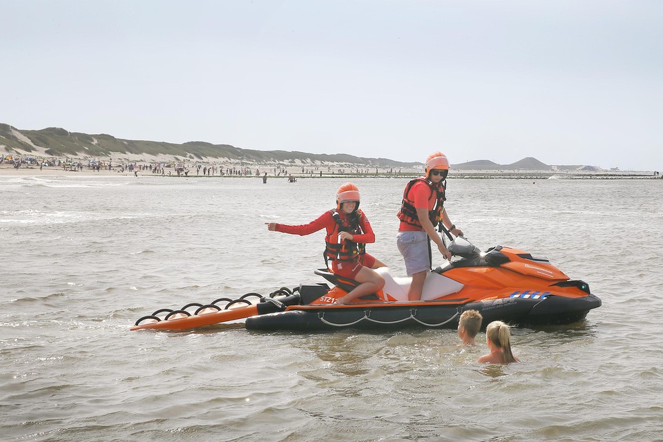 Annelotte Weert (l) en Damiën Vonk van de Reddingsbrigade geven tijdens een waterscooterpatrouille zwemmende kinderen aanwijzingen.