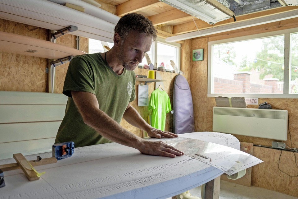Peter Ottervanger werkt geconcentreerd aan een surfboard.